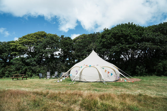 Outback Tents. Picture of a Lotus Belle Tent pitched in a field. A luxury, canvas bell tent, but with lots of standing room. Perfect for glamping, events & parties